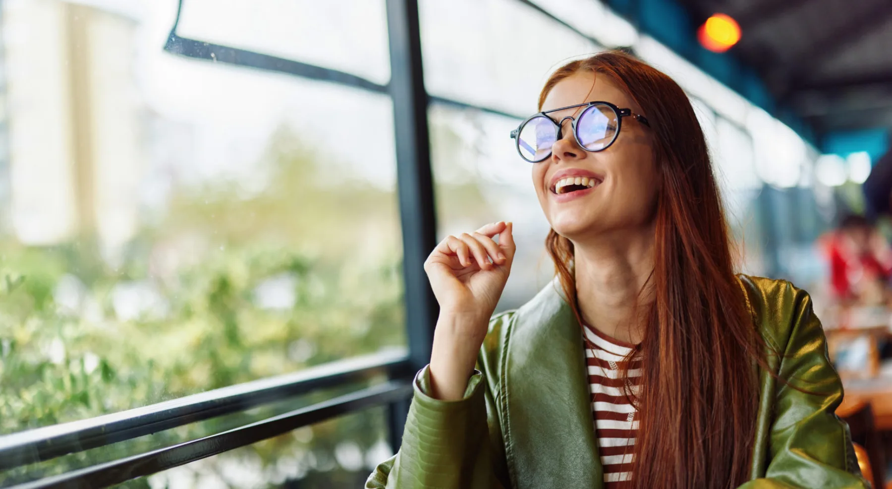 Smiling woman wearing round eyeglasses in a bright café